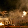 A still from the film "RRR." The still depicts a tiger and a man jumping into the air towards each other against a smoky, dark background.