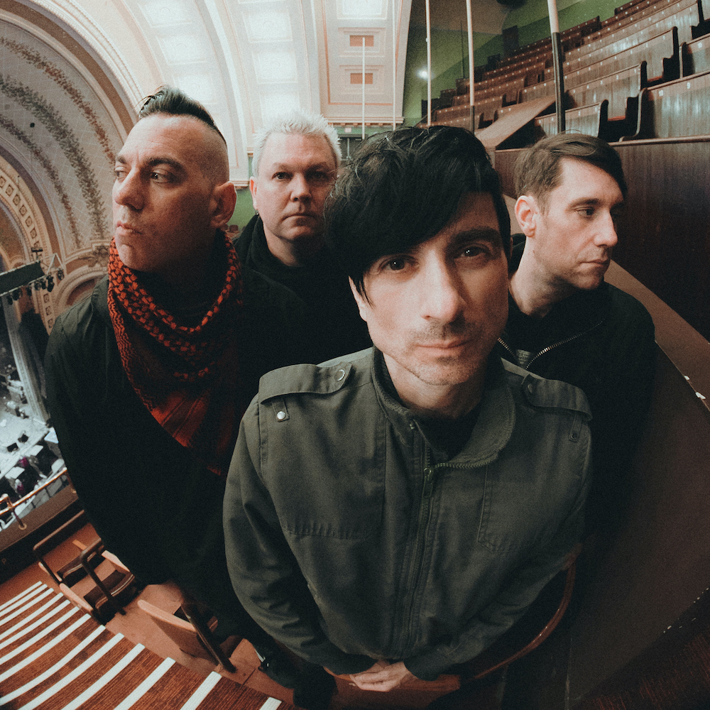 A promotional picture of the band Anti Flag. They are posing in a theater and there is a fisheye effect on the image.