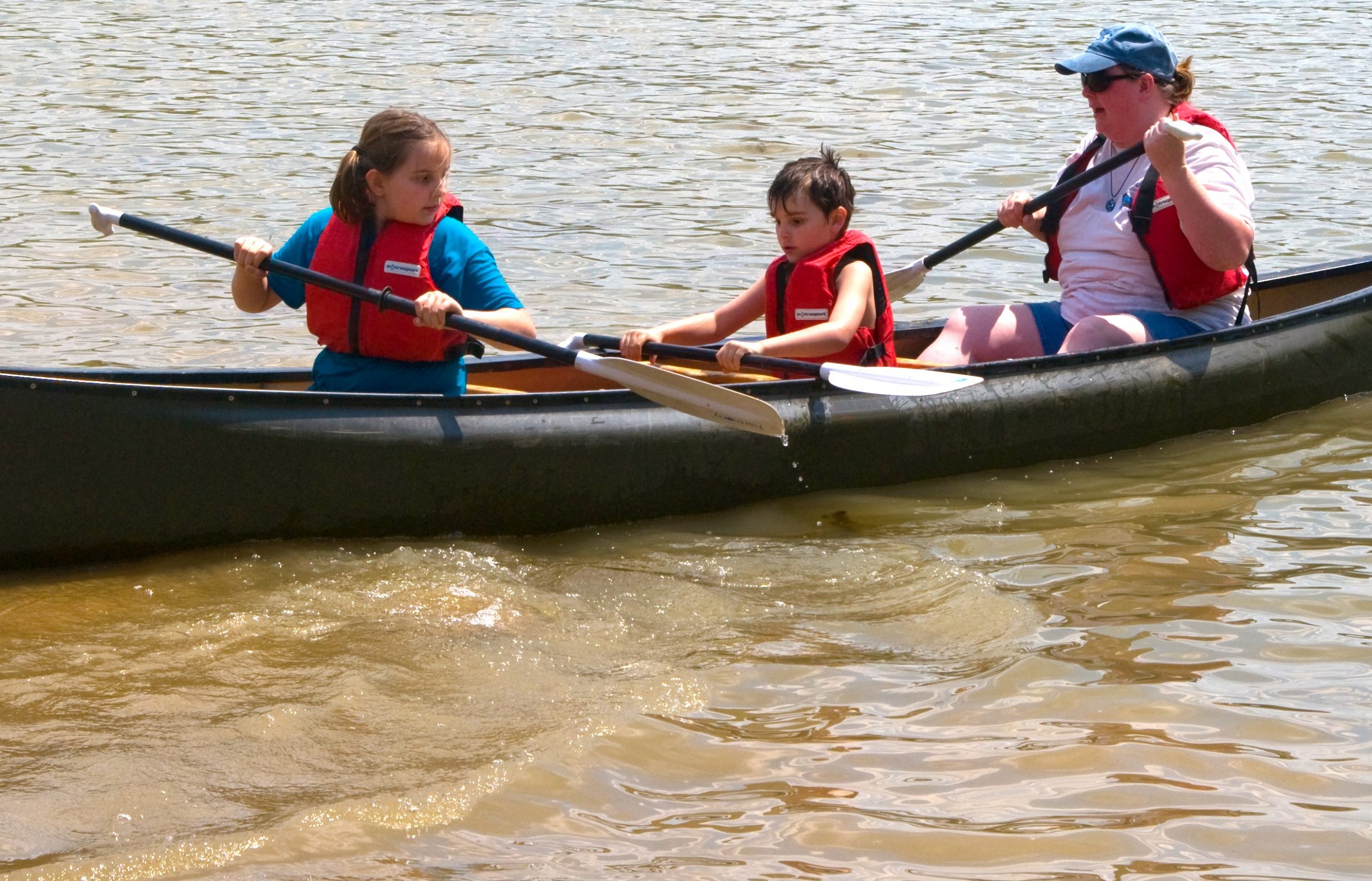 An image of three people in a canoe wearing orange safety vests.