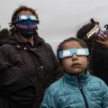 A Mapuche Indigenous family uses special glasses to try and observe a total solar eclipse in Carahue, La Araucania, Chile