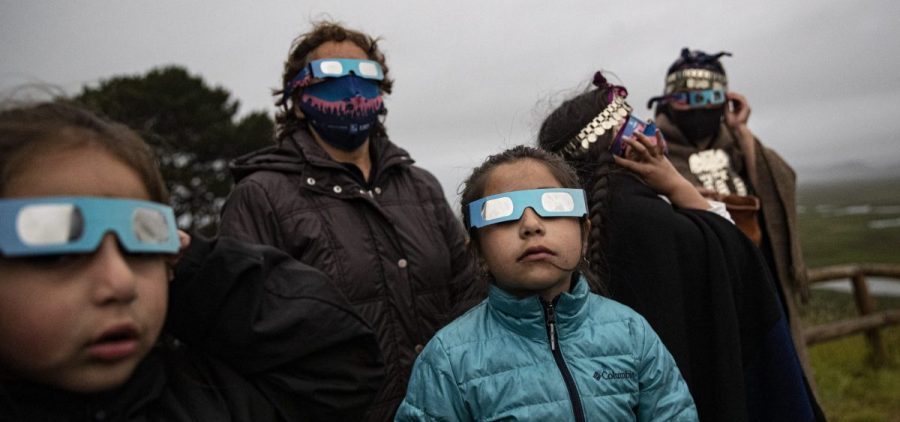 A Mapuche Indigenous family uses special glasses to try and observe a total solar eclipse in Carahue, La Araucania, Chile