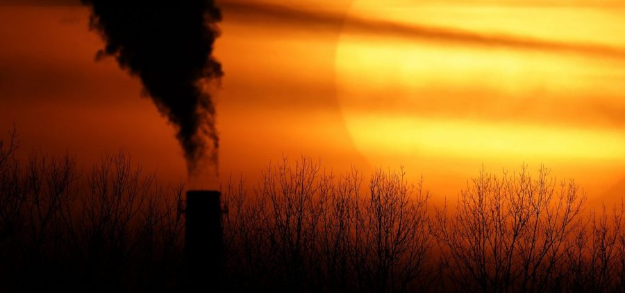 Emissions from a coal-fired power plant are silhouetted against the setting sun in Kansas City, Mo.