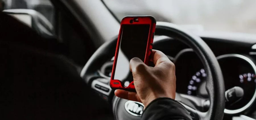 A person holds their phone while behind the wheel of a car