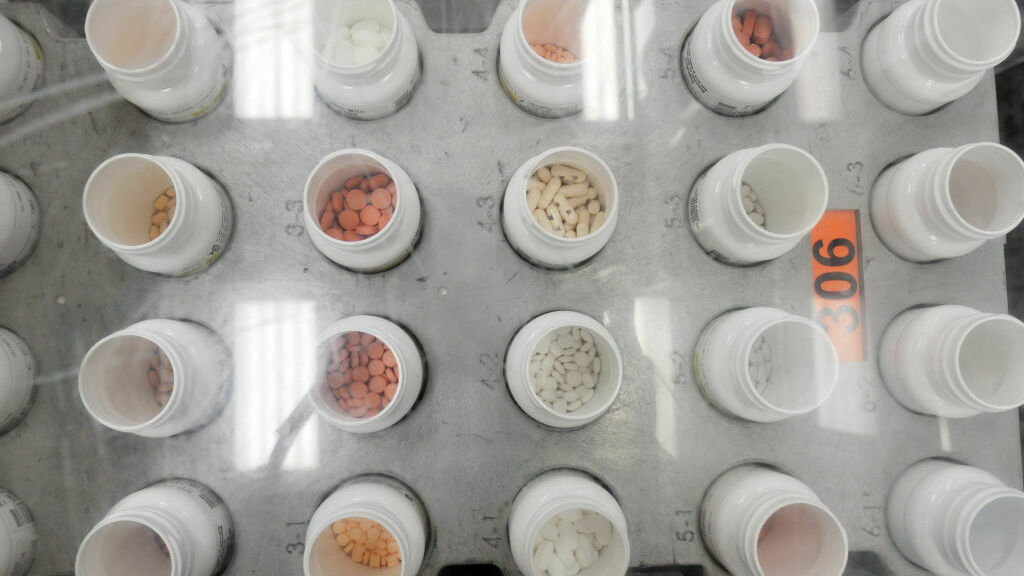 Bottles of prescription pills go through an automated packaging machine in a pharmacy plant.