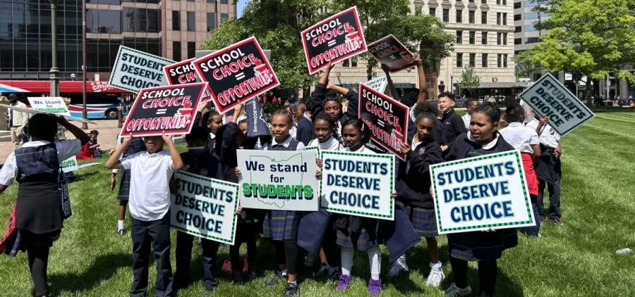 A group of parochial school students hold signs to encourage expansion of the state's voucher program at a rally outside the Ohio Statehouse