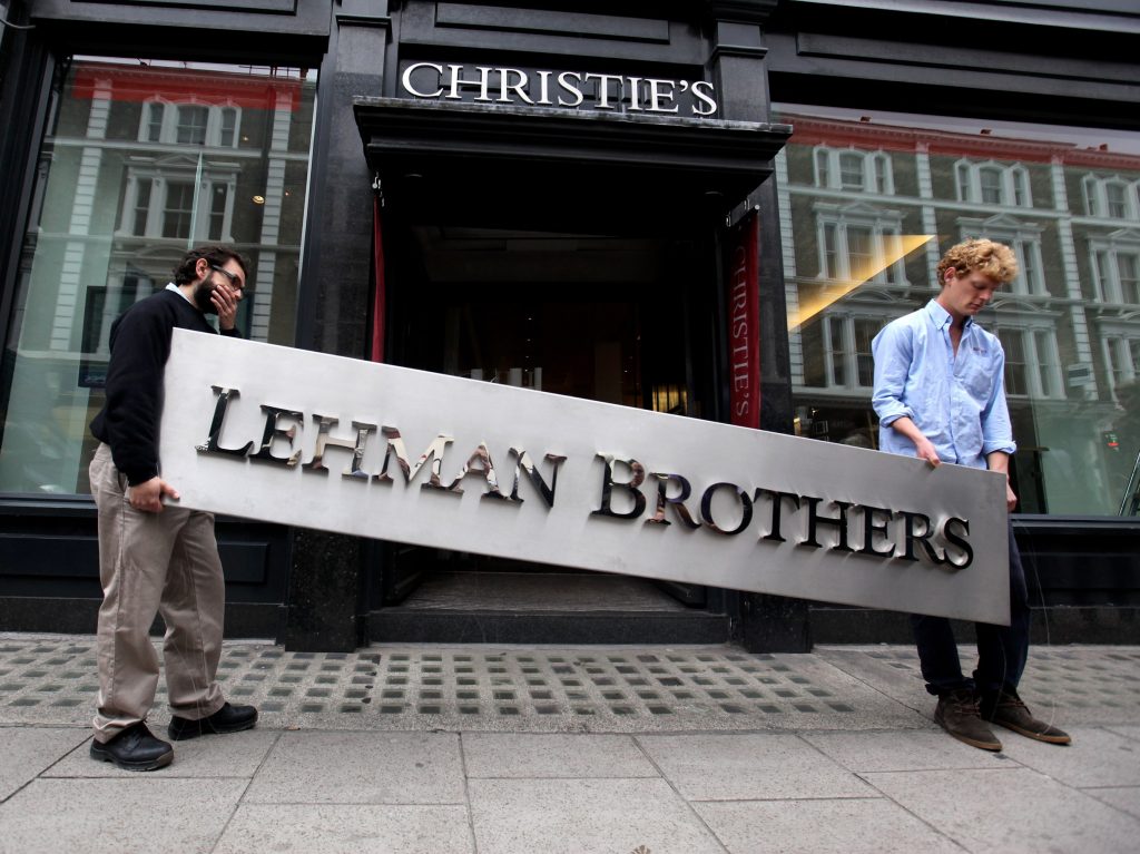 Two employees of the auction house Christie's bring down the Lehman Brothers corporate logo in London, England, on Sept. 24, 2010.