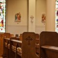 Empty church pews fill a sanctuary with stained glass windows
