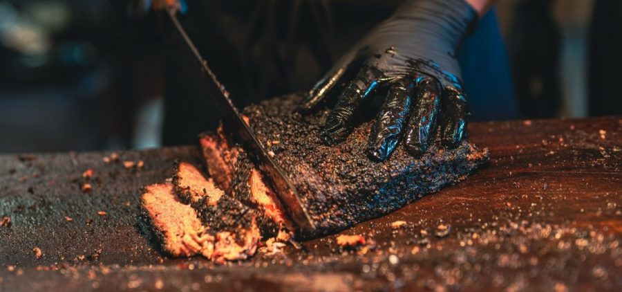 A knife slices into a blackened brisket.