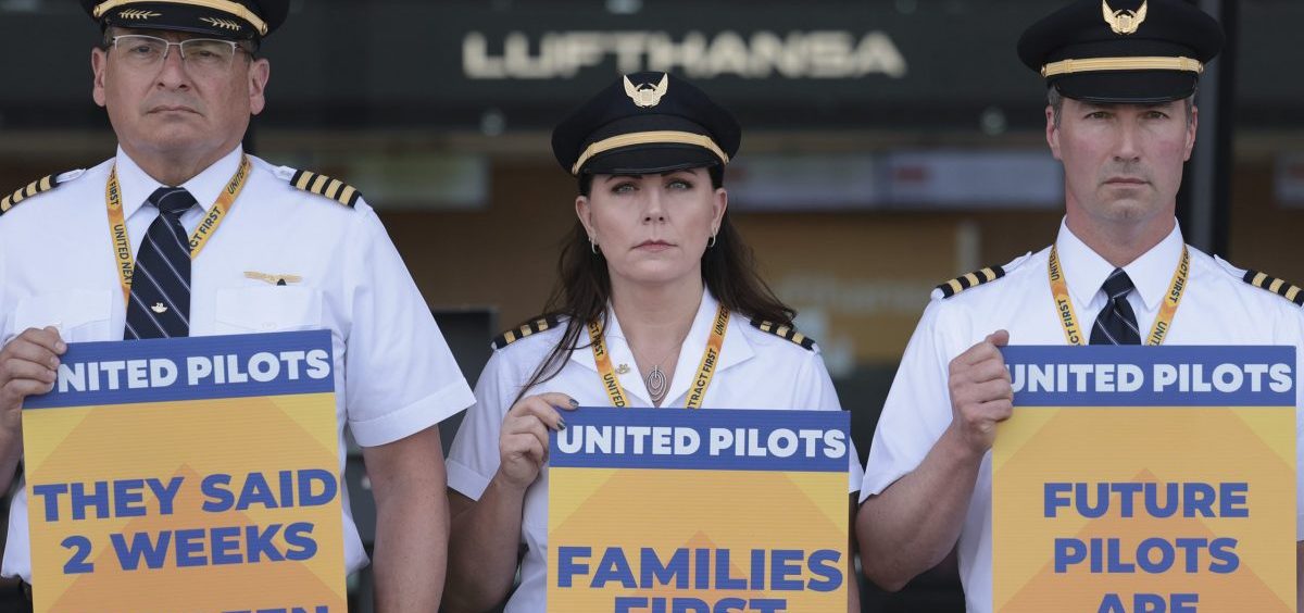 United Airlines pilots participate in a picket line at Washington Dulles International Airport on May 12, 2023. They hold blue, white and yellow picket signs.