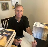 Jeff Stewart signs one of his books while sitting at a desk
