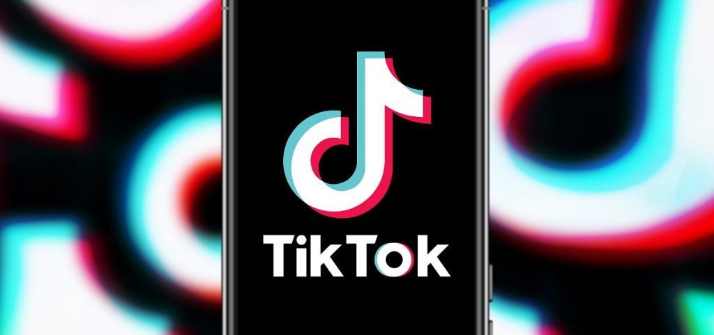 A smartphone displays the TikTok logo with a backdrop of TikTok logos