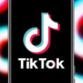 A smartphone displays the TikTok logo with a backdrop of TikTok logos