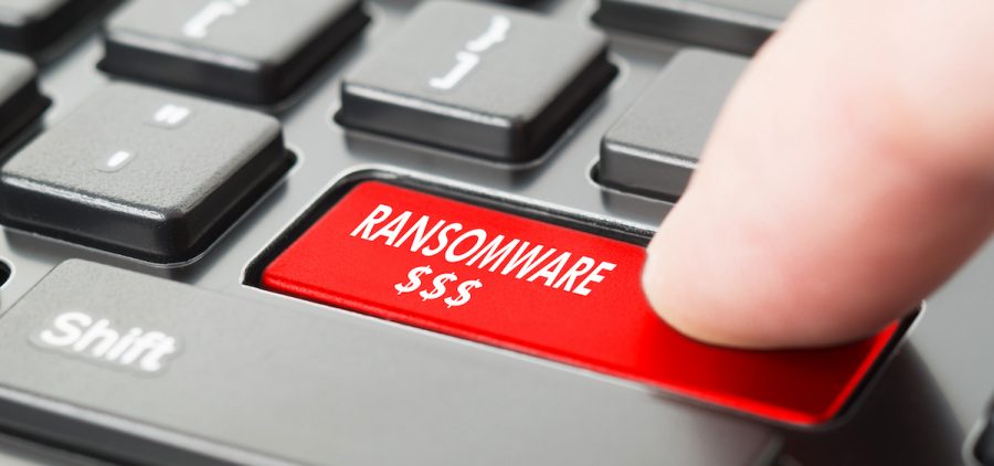 Ransomware written on keyboard button with finger pressing on it.