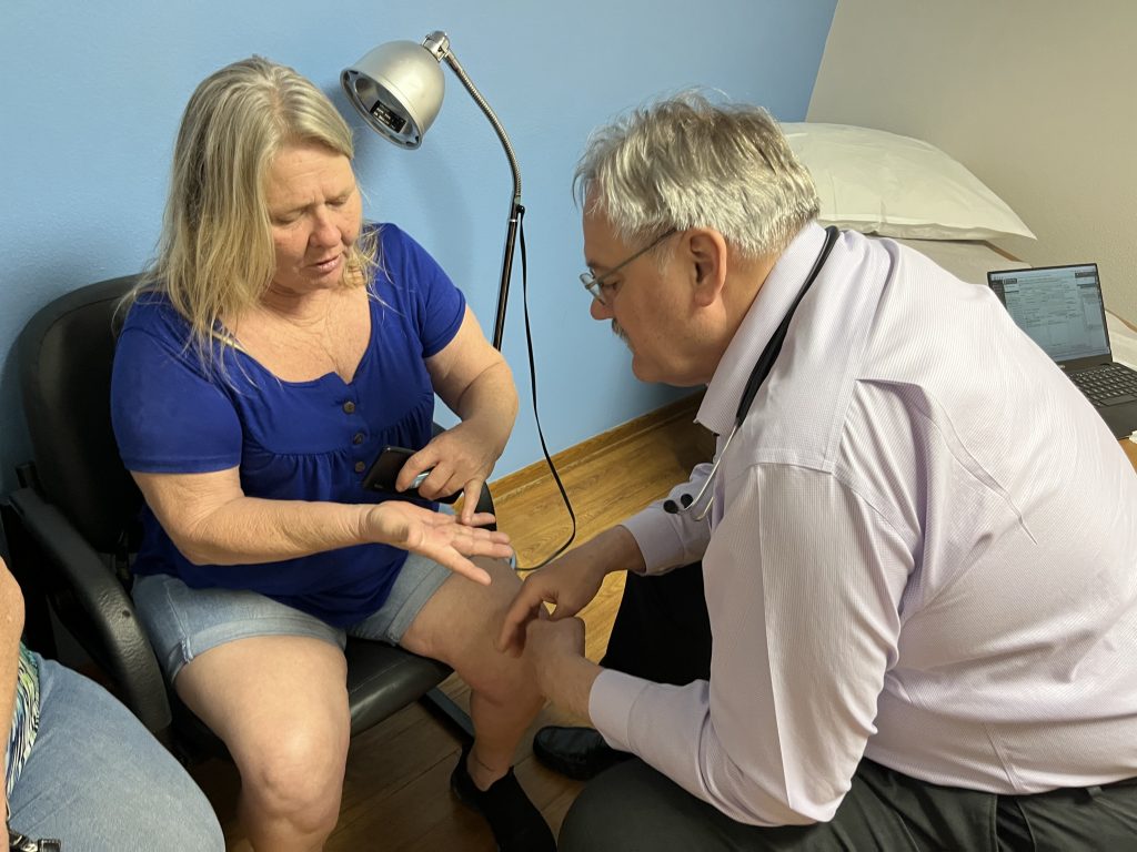 Alice Collins of Winterset, Iowa, shows osteopathic physician Kevin de Regnier a spot on her hand during an office visit in May. A surgeon recently removed a tumor from her hand.