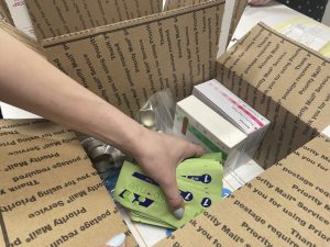 A hand places fentanyl drug test strips into a shipping box.