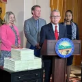 Ohio Gov. Mike DeWine (center, in red tie) speaks to reporters about signing the two-year state budget. Alongside him are (l-r): Ohio Medicaid Director Maureen Corcoran, Office of Budget and Management Director Kim Murnieks, Lt. Gov. Jon Husted, Ohio Department of Aging Director Ursel McElroy and Department of Mental Health and Addiction Services Director Lori Criss.