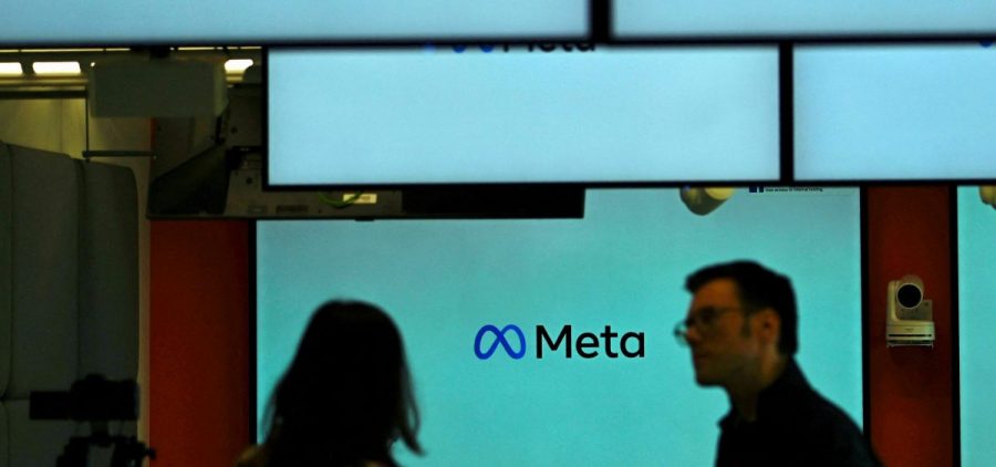 Visitors stand near screens displaying the Meta logo in Berlin