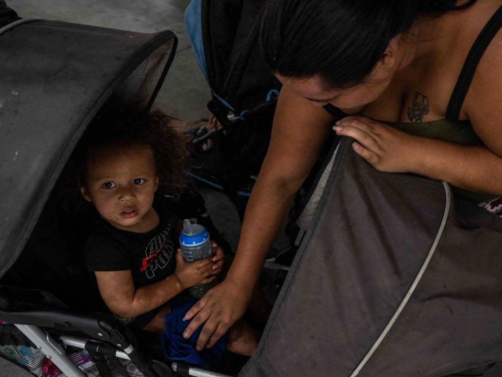 A woman wipes her son with a wet cloth as her family waits at a bus station in Tucson, Ariz.