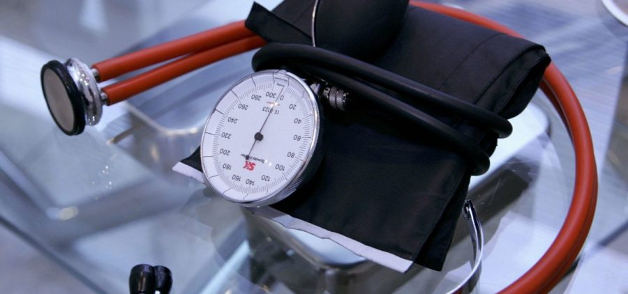A stethoscope and a blood pressure device lay on a glass table.
