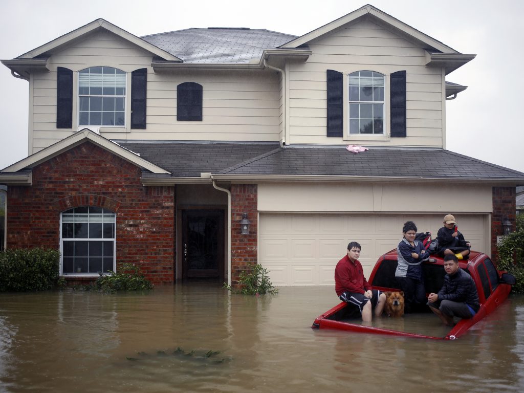 A family sits on a pickup half-submerged in floodwater.