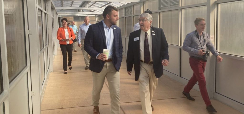 Rep. Jay Edwards and Bruce Nottke chat while walking down a hallway with a glass roof at Tri-County Career Center.
