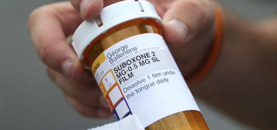 A person pulls a Suboxone pill bottle out of the bag.