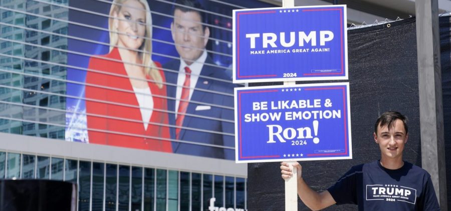 A former President Donald Trump supporter stands near the Fiserv Forum Tuesday as setup continues for Wednesday's Republican presidential debate in Milwaukee.