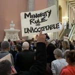 Demonstrators in the Ohio statehouse, one is holding a sign up that reads minority rule is unacceptable
