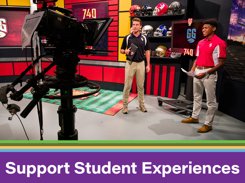 College students in a sports TV studio during a program. Web button to support the WOUB student experience.