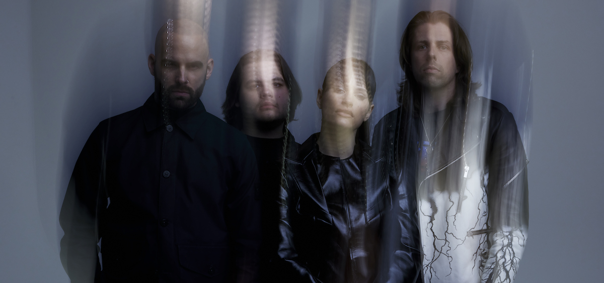 A promotional image of the band Spiritbox. It is slightly distorted and shows all four members wearing all black.