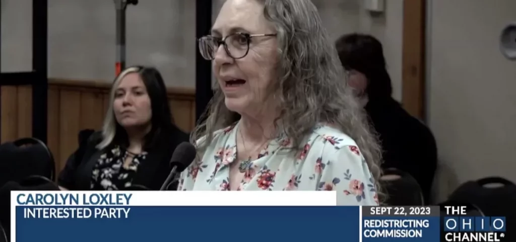 Carolyn Loxley, a woman with long, wavy gray hair, testifies to the Ohio Redistricting Commission