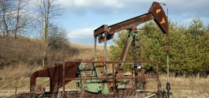 A rusted oil well pump in Ohio sits in a field