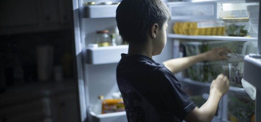 A child reaches for something in a refrigerator.