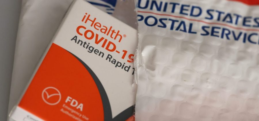 A COVID testing kit is slightly out of a USPS package.