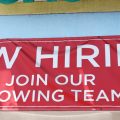A 'Now Hiring' sign is displayed outside a check cashing shop in Los Angeles on June 2, 2023.