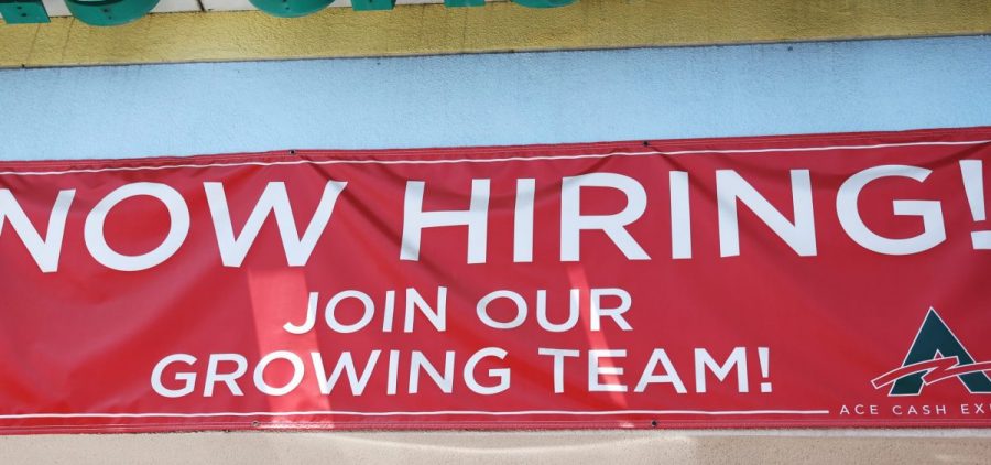 A 'Now Hiring' sign is displayed outside a check cashing shop in Los Angeles on June 2, 2023.