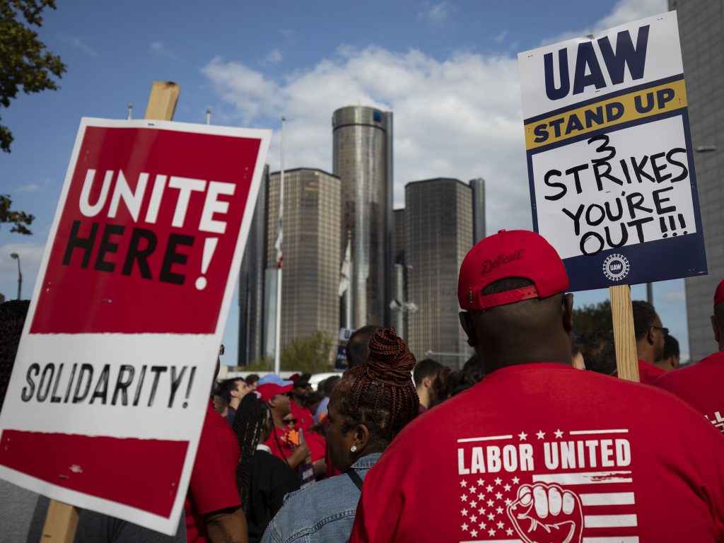 A crowd of United Auto Workers hold up signs to support striking workers.
