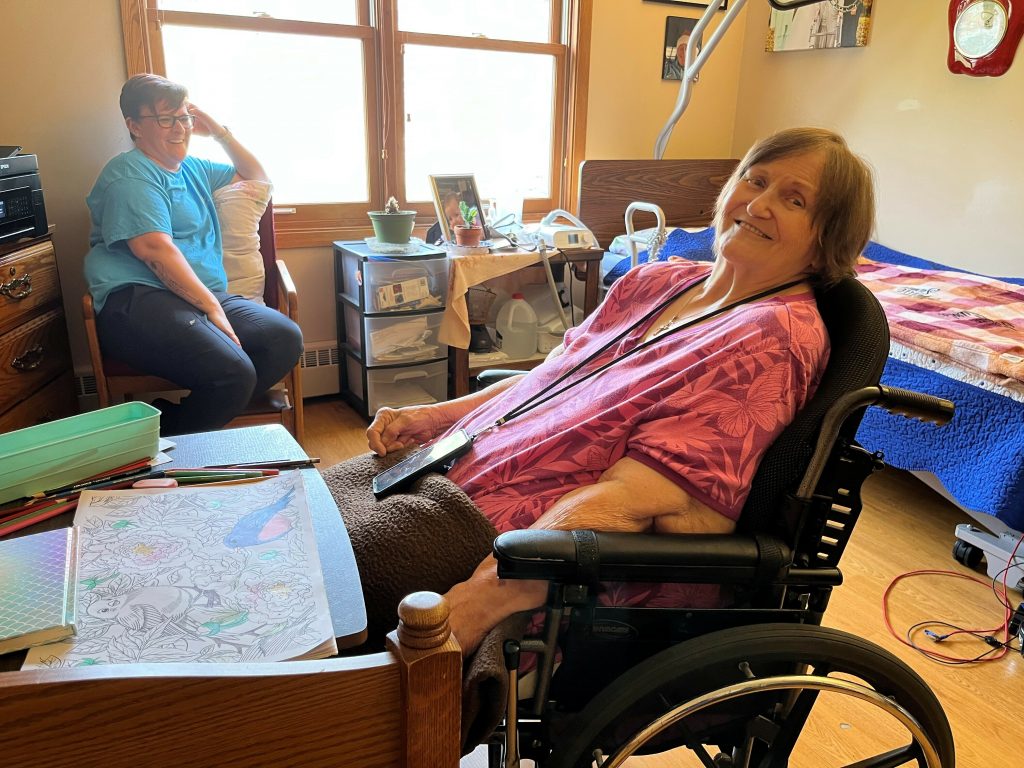 Nellie Swale, a resident of Good Samaritan in Syracuse, Nebraska, hangs out with Karena Cunningham, a certified nursing assistant in her room