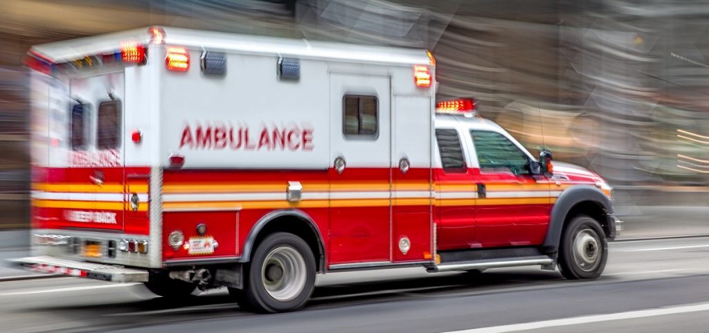 An ambulance drives down the road with the background blurred.