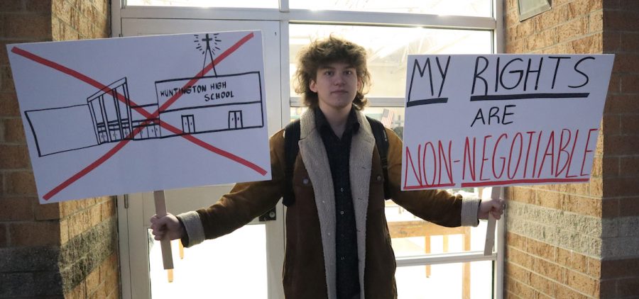 Huntington High School senior Max Nibert holds signs he plans to use during a walkout students are staging at Huntington High School in Huntington, W.Va.