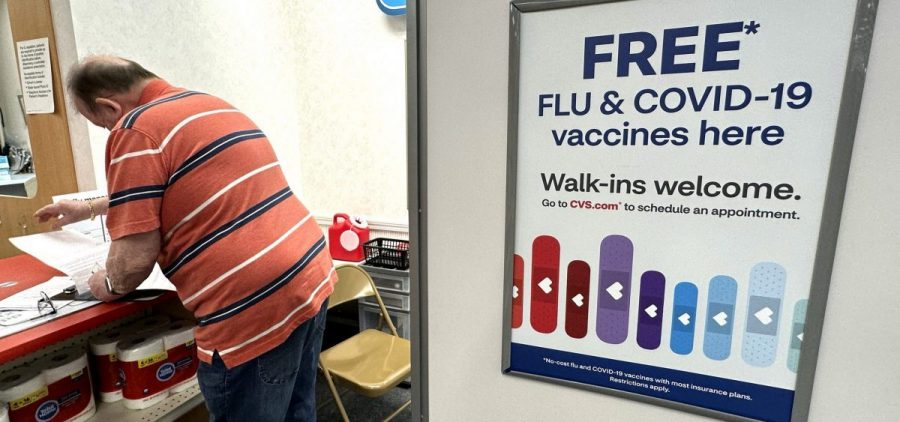 A sign for flu and covid vaccinations is displayed at a CVS pharmacy store.
