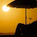 A person rests under an umbrella as the sun sets