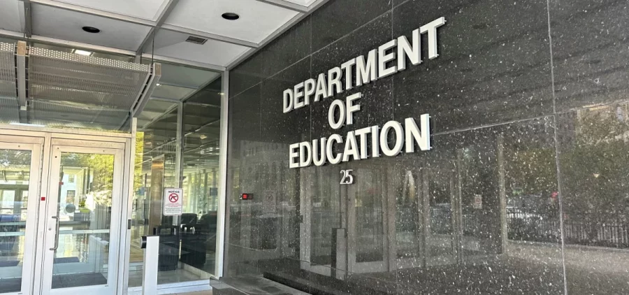 The words "Department of Education" are on the side of a building in white outside of the department of education's building