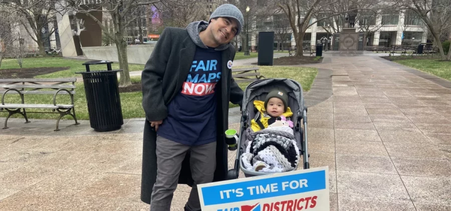 A father and child in a stroller attend a protest over redistricting at the Ohio Statehouse