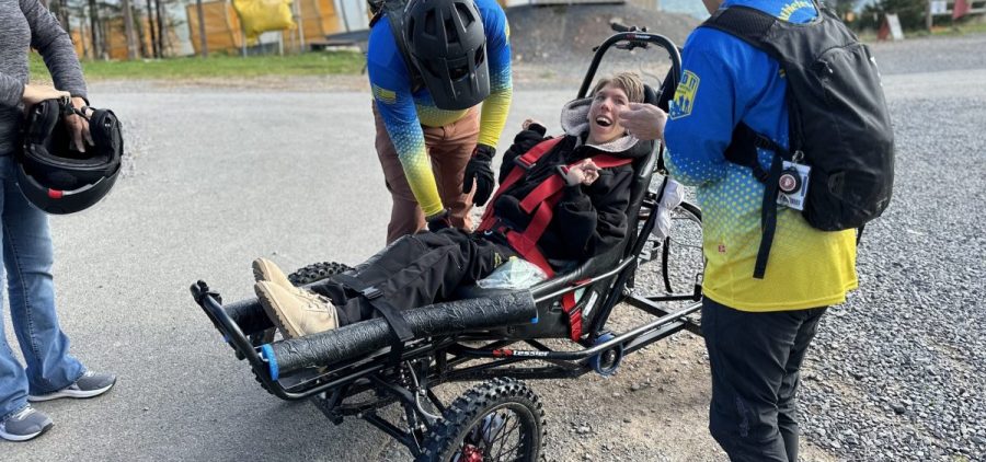 Carol Woody and volunteer Erwin Berry make sure Gage Tatar is safely buckled into the Cimgo. The Cimgo is like a heavy duty wagon that you push from the back but instead of walls on it, it has roll bars. Grinning wide, Tatar listens as Woody explains what he can expect on the dirt track.