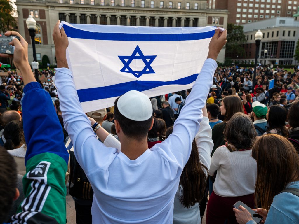 A man holds up an Israeli flag as Columbia University students participate in a rally in support of Palestine at the university on Oct. 12 in New York City.