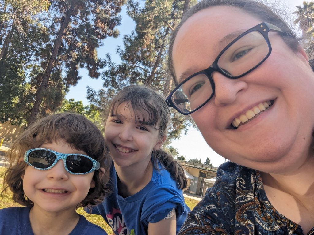 Anne Hamilton with two of her children, 11-year-old Katie and 4-year-old Jimmy, pose for a selfie outside with trees nearby.