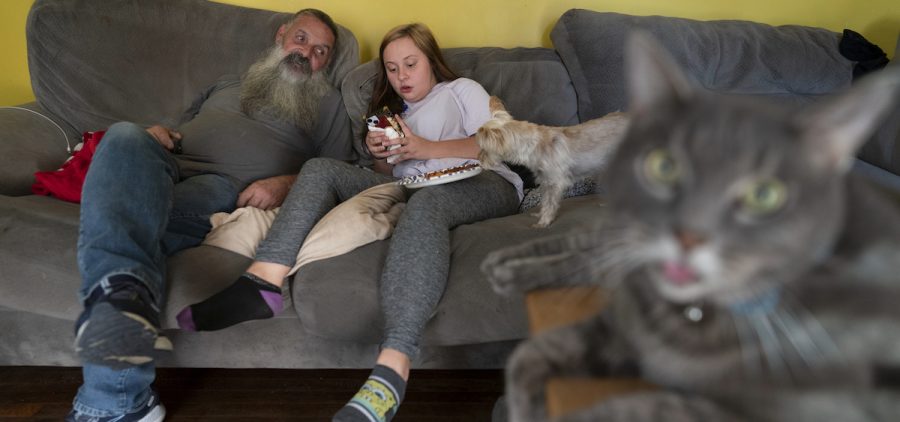 Joe Smith talks with his granddaughter Olivia on the couch in their home in Columbus, Ohio, Tuesday, Oct. 24, 2023, with their cat Marshall and dog Presley.