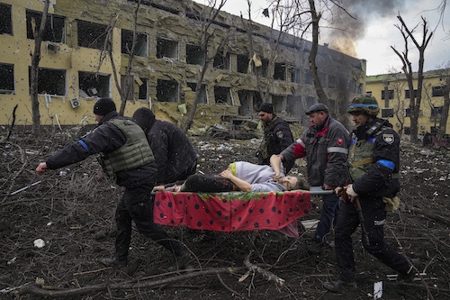 Українські надзвичайники та волонтери несуть поранену вагітну жінку на маленьких ношах із червоною ковдрою з пологового будинку, який постраждав від авіаудару в Маріуполі, Україна, 9 березня 2022 року.