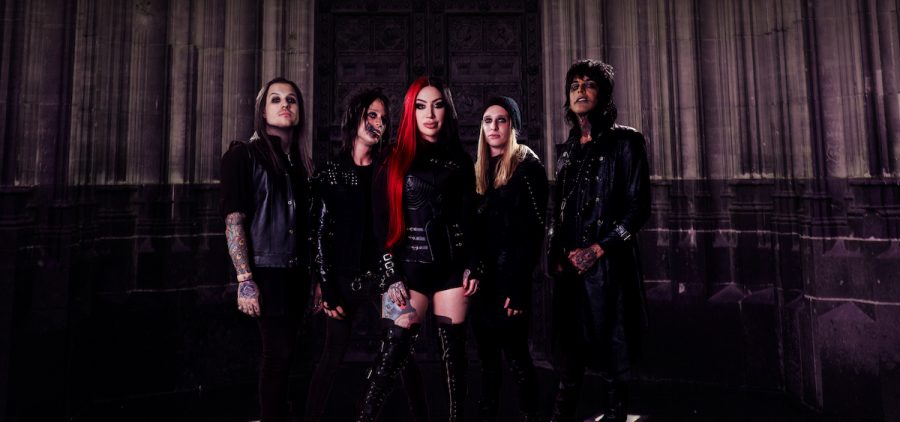 A promotional image of the band New Year's Day. They group is posed in a dark room and wearing the kind of clothes you would associate with a heavy metal band.